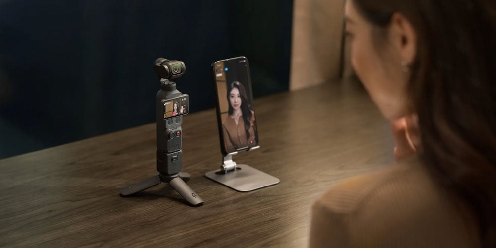 someone using the dji osmo pocket 4 connected to a smartphone