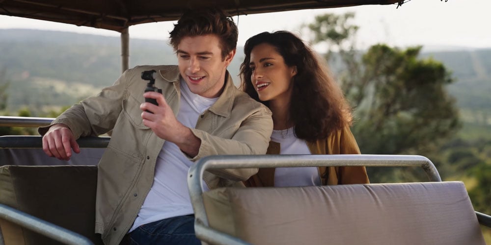 a couple using the dji osmo pocket 4 to film while on a safari
