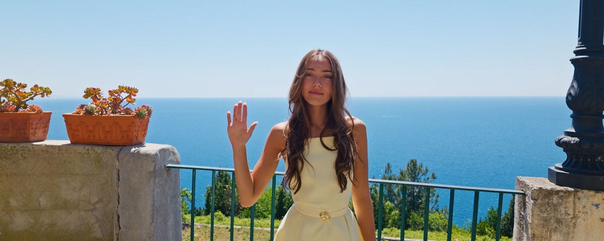 a woamn standing in front a railing over looking the ocean making a gesture to start tracking on the osmo pocket
