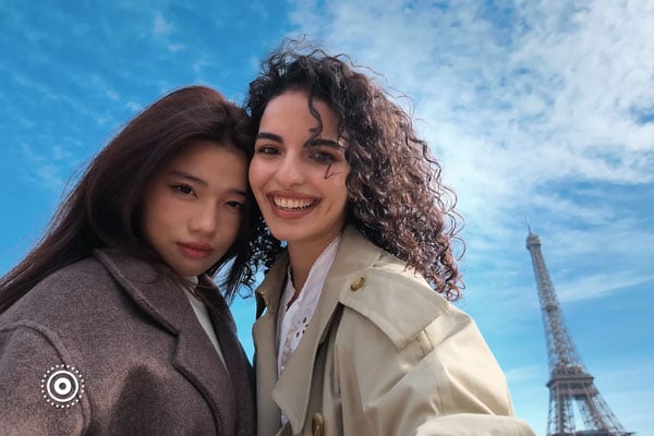 two women taking a photo in front of the eiffel tower using live photo