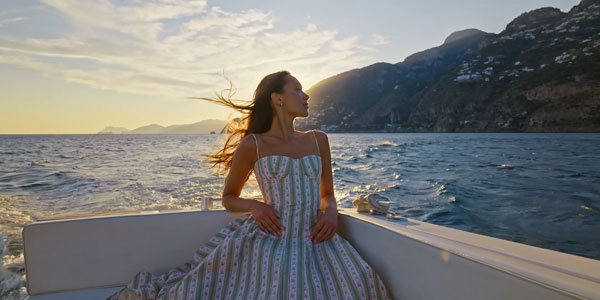 backlight portrait of a woman leaning against the edge of a boat over the ocean