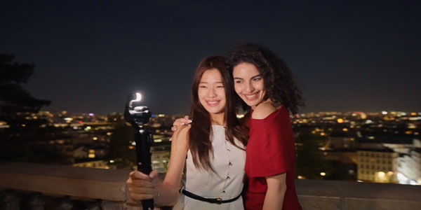two women taking a selfie in front of a city skyline