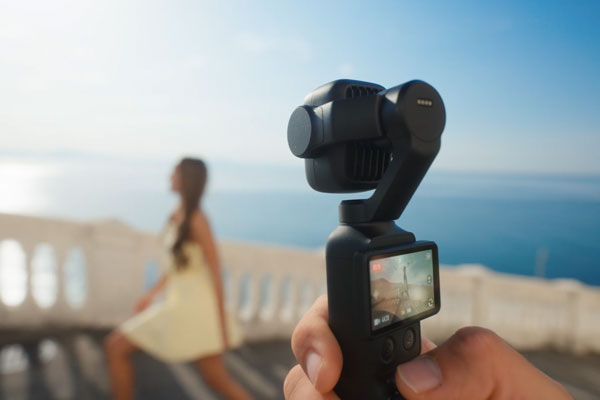 behind camera view of the gimbal while filming a woman walking up some stairs