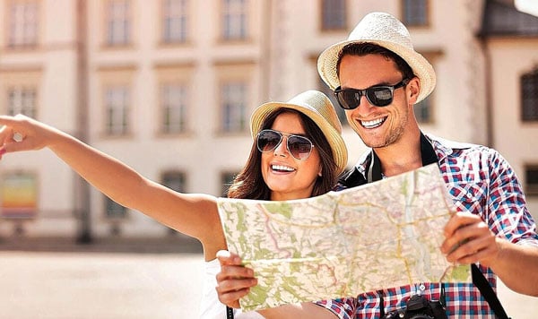 Happy couple holding map and pointing to destination while traveling