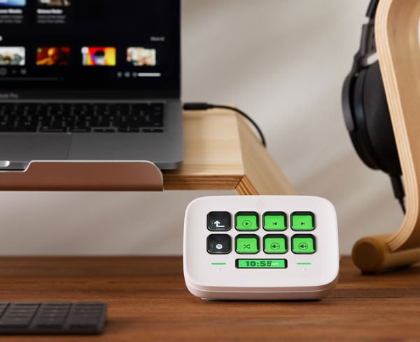 Elgato Stream Deck Neo on a desk with a laptop and headset on a stand