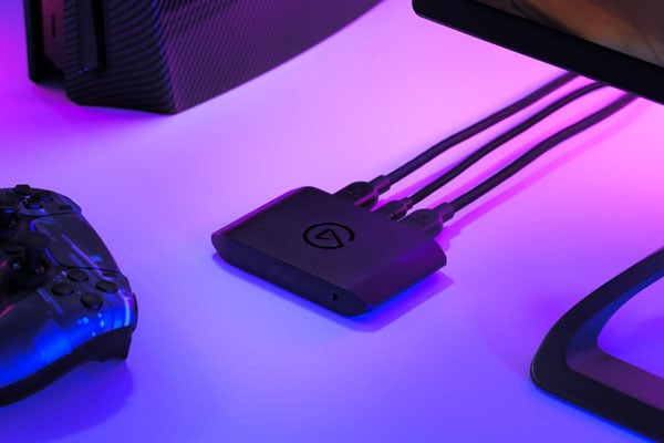 Elgato Game Capture 4K X external capture card resting on a desk under purple and pink ambient lighting