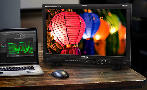 flanders monitor set up on a wooden desk next to a laptop showing video scopes