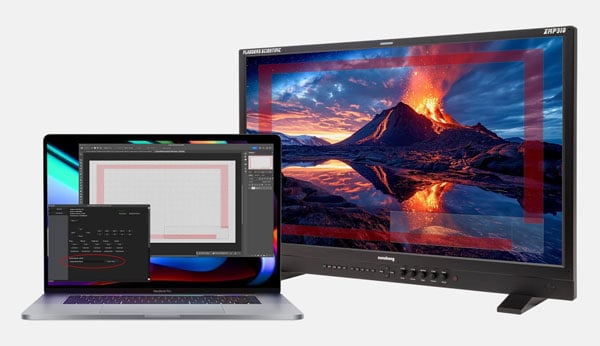 Laptop connected to an external professional monitor displaying a high-definition volcano landscape for video editing