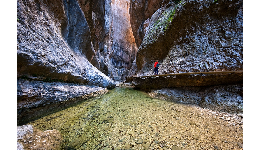 Fujifilm XF8mm F3.5 R WR Sample Image of person walking though a rocky canyon with slow moving water
