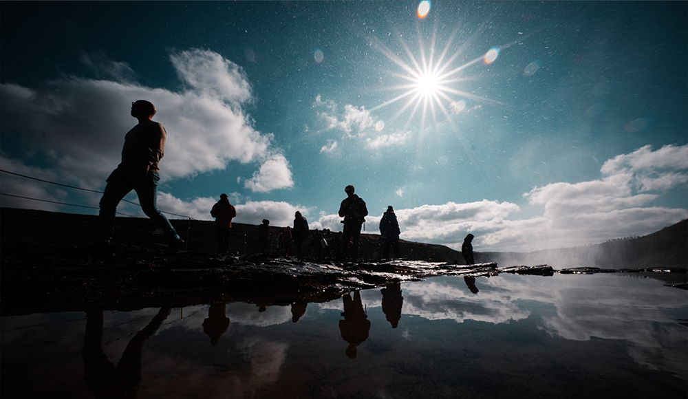 Fujifilm XF8mm F3.5 R WR sample image of preople walking along the edge of a rock pool silhouetted against the sky