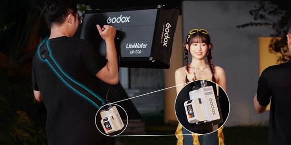 someone wearing the shoulder strap and battery pack while using the godox light
