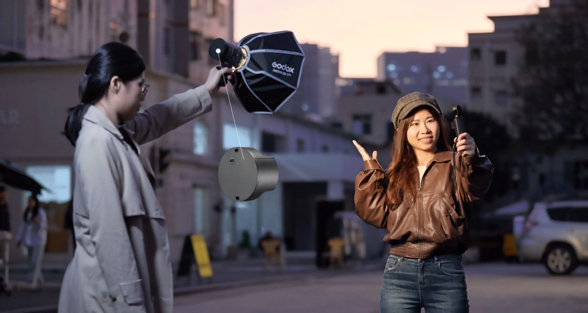 a woman being filming with an action camera while someone holds the godox light