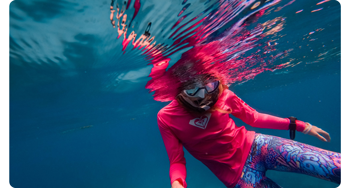Diver wearing bright pink shirt and snorkel under water 