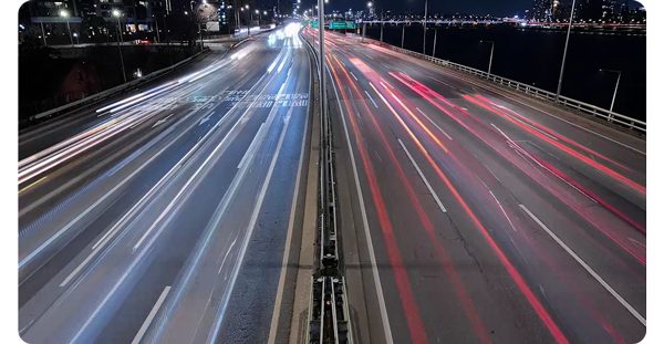 vehicle light trail photograph from standing above highway showing both sides of traffic