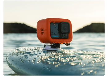GoPro HERO13 Black in orange float case mounted to surfboard out in the ocean at sunrise
