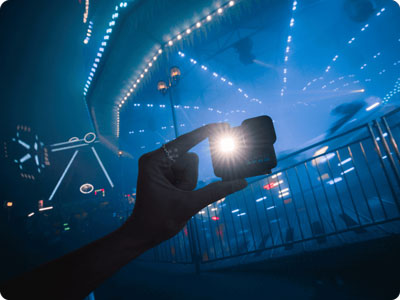someone holding the gopro camera at a carnival in the dark