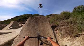 BMX riders performing tricks over dirt ramps