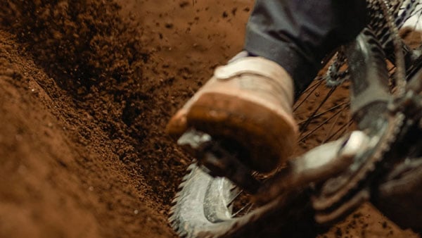 sample image of a rider's foot clipped into a mountain bike pedal while going through dark soil