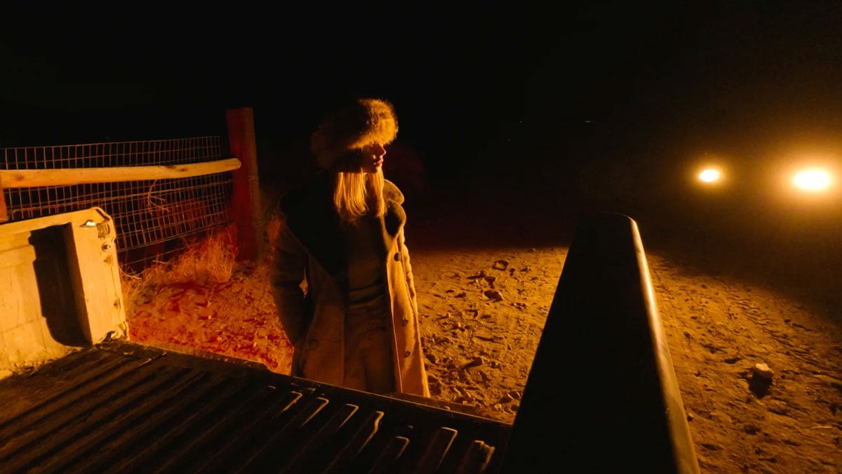sample image of a woman stood behind a truck wearing a fur hat and long coat at night
