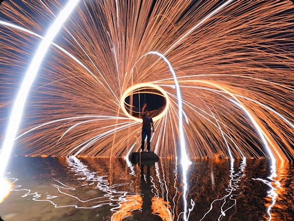 somone light painting in the middle of a lake