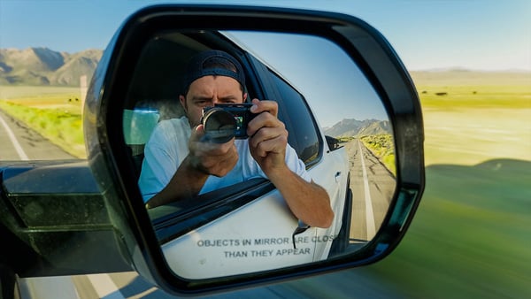 sample image of a man filming using the gopro mission 1 pro ils in a wing mirror of a car