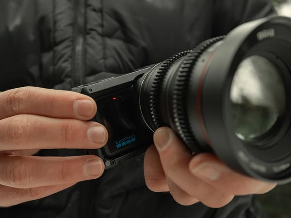 someone holding the gopro mission 1 pro ils with a telephoto lens attached