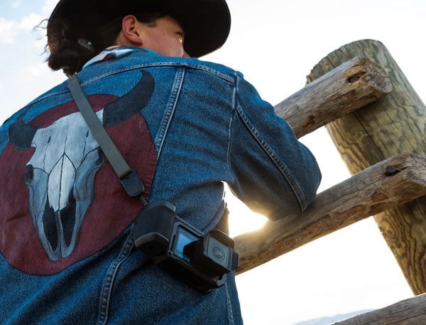 a cowboy wearing the gopro mission 1 in the point-and-shoot grip while leaning against a fence
