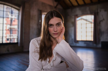hasselblad sample photograph of female model sitting in classic studio with large bay windows