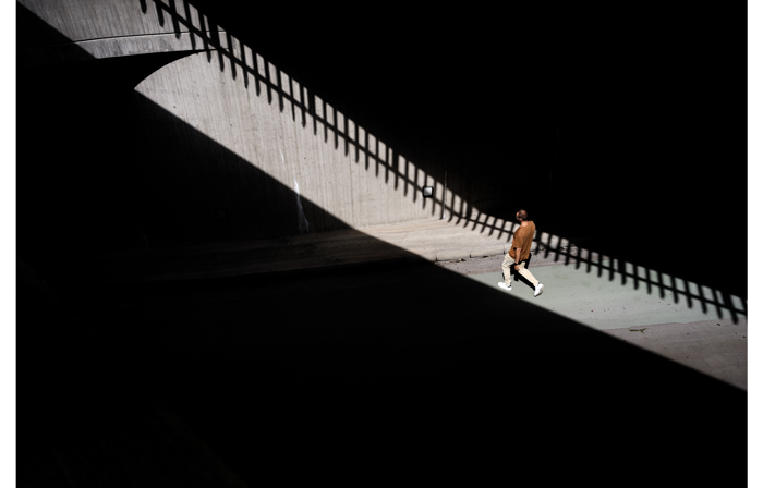 hasselblad X2D XCD 4/28P Sample image of a man whling across a street that is draped in shadow with a small gap of bright sunlight 