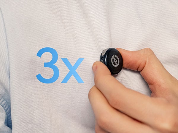 A hand attaching the hollyland lark m3 trasnsmitter to a their shirt next to a blue 3x graphic on fabric