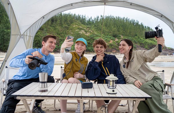 A group of friends taking a selfie and holding cameras while wearing hollyland mics