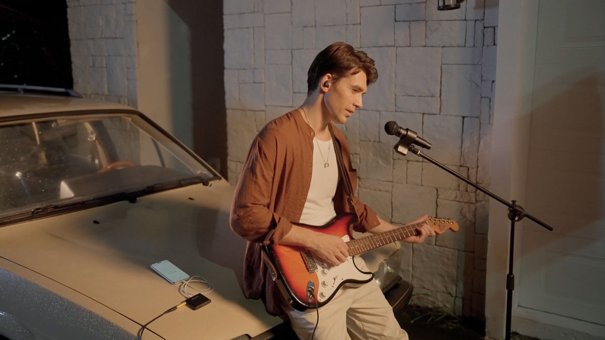a musican recording using the melo p1 while playing a guitar on a car bonnet