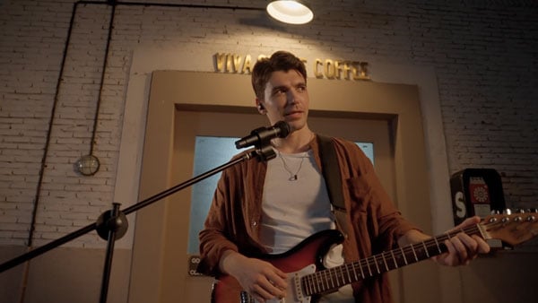 a musican recording using the melo p1 while playing a guitar putside a coffee shop