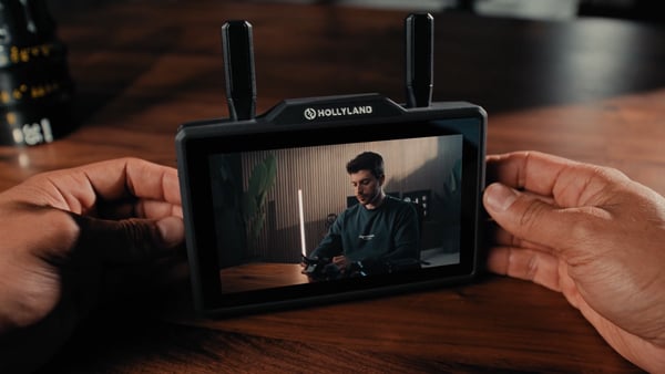 Hollyland Pyro 5 wireless transceiving monitor held by a videographer on a wooden table