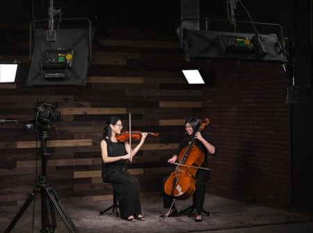ikan led lights being used in a studio while 2 people play classical music