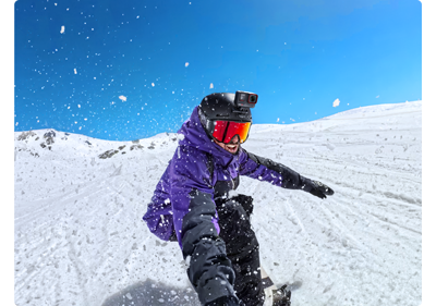 photo of snowboarder riding down a ski slope holding selfie stick with Insta360 ace pro 