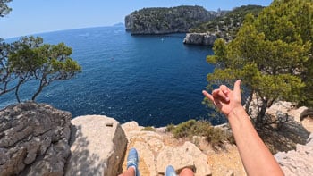 wide angle image of person sitting on cliff edge over looking the ocean