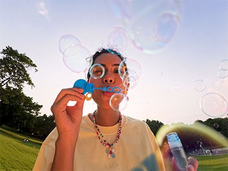 sample photograph of woman blowing bubbles at camera