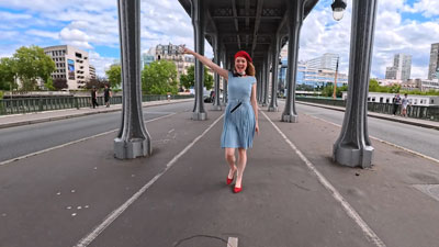 woman dancing under railway overpass on footpath 
