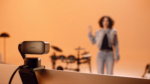 insta360 link 2 pro on top of a monitor tracking a person in a orange music studio
