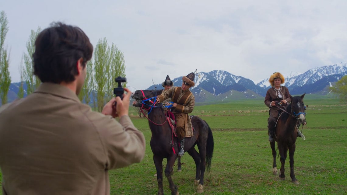 a man filming three men on horses