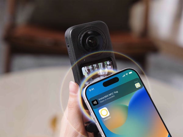someone tapping a smart phone on the insta360 x6 to connect to the mobile app