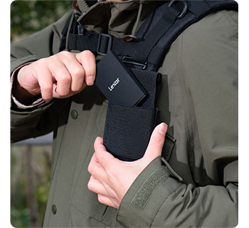 Person sliding Lexar Armor 700 SSD into chest pocket on backpack straps