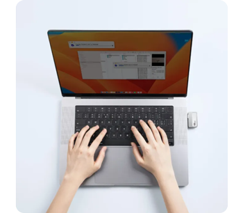 person typing on apple macbook with Lexar Go Portable SSD connected 