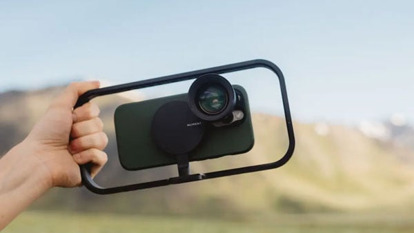 someone holding a smartphone in the moment cage with the tele mobile lens connected