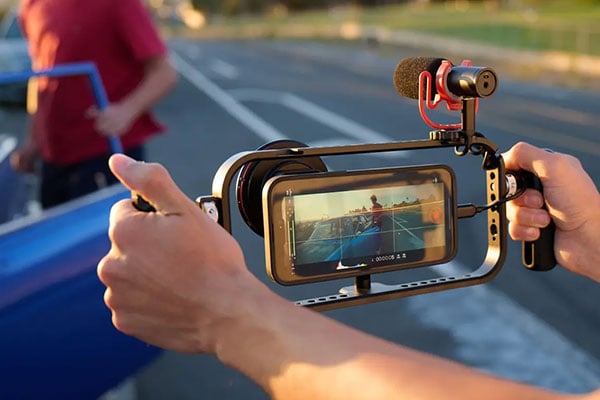 someone filming someone getting into a car using their phone in a moment case and cage