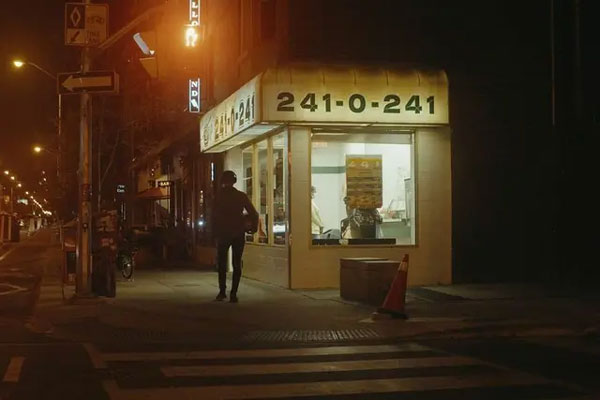 example image using the diffusion filter as someone crosses a street near a shop at night time