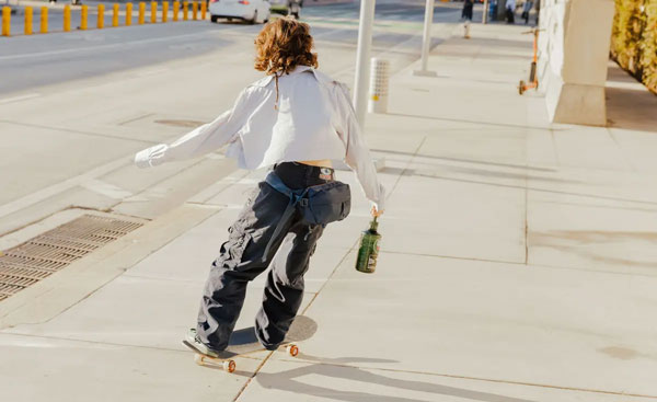 skateboarder going down a street with the sling bag around their waist