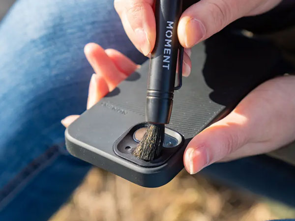 the mobile lens cleaning brush being used to a clean a phone camera