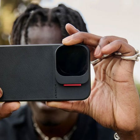 someone taking a photo using a smart phone in a moment case with the vnd filter attached